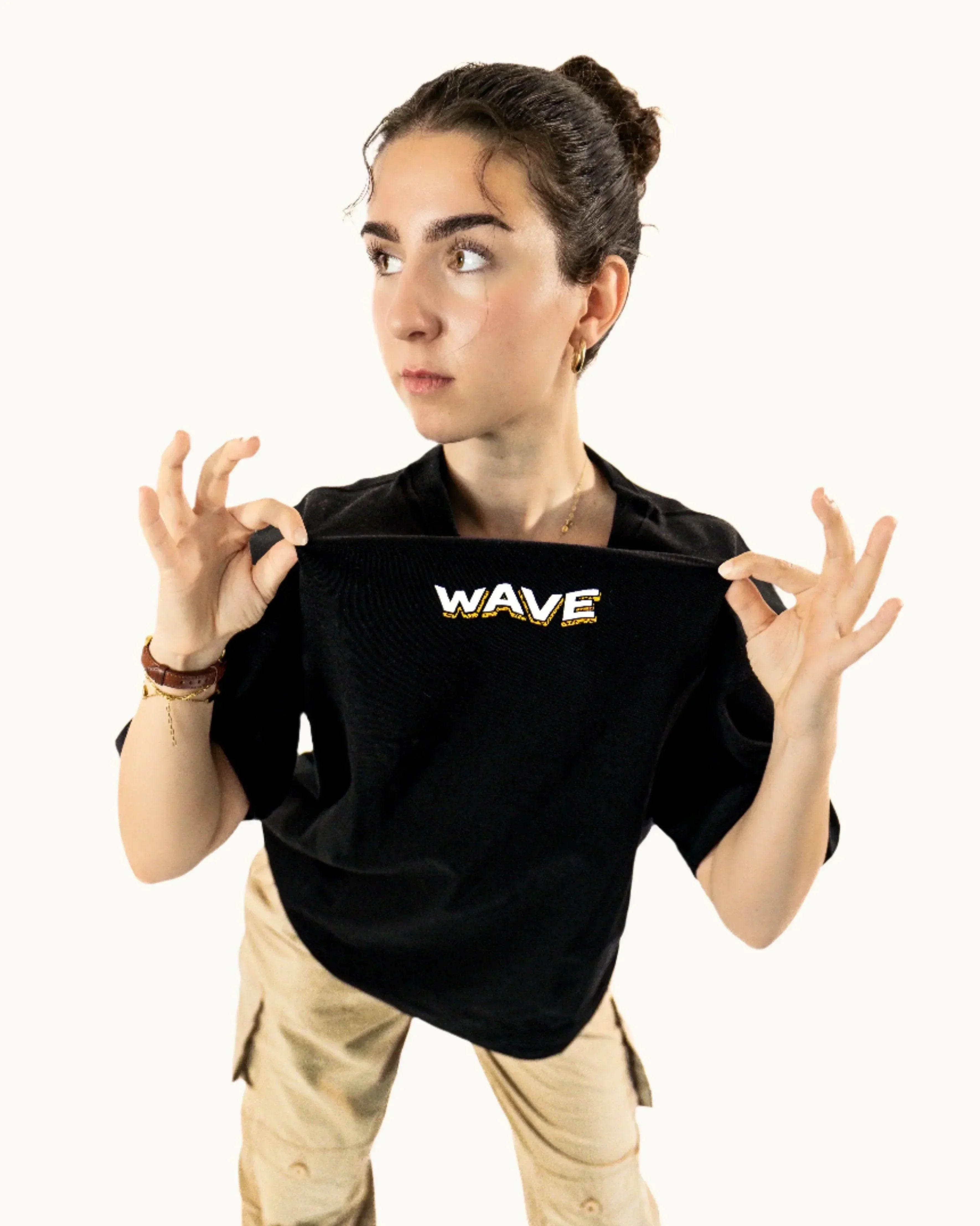 Woman wearing black WAVE t-shirt and beige cargo pants on white background