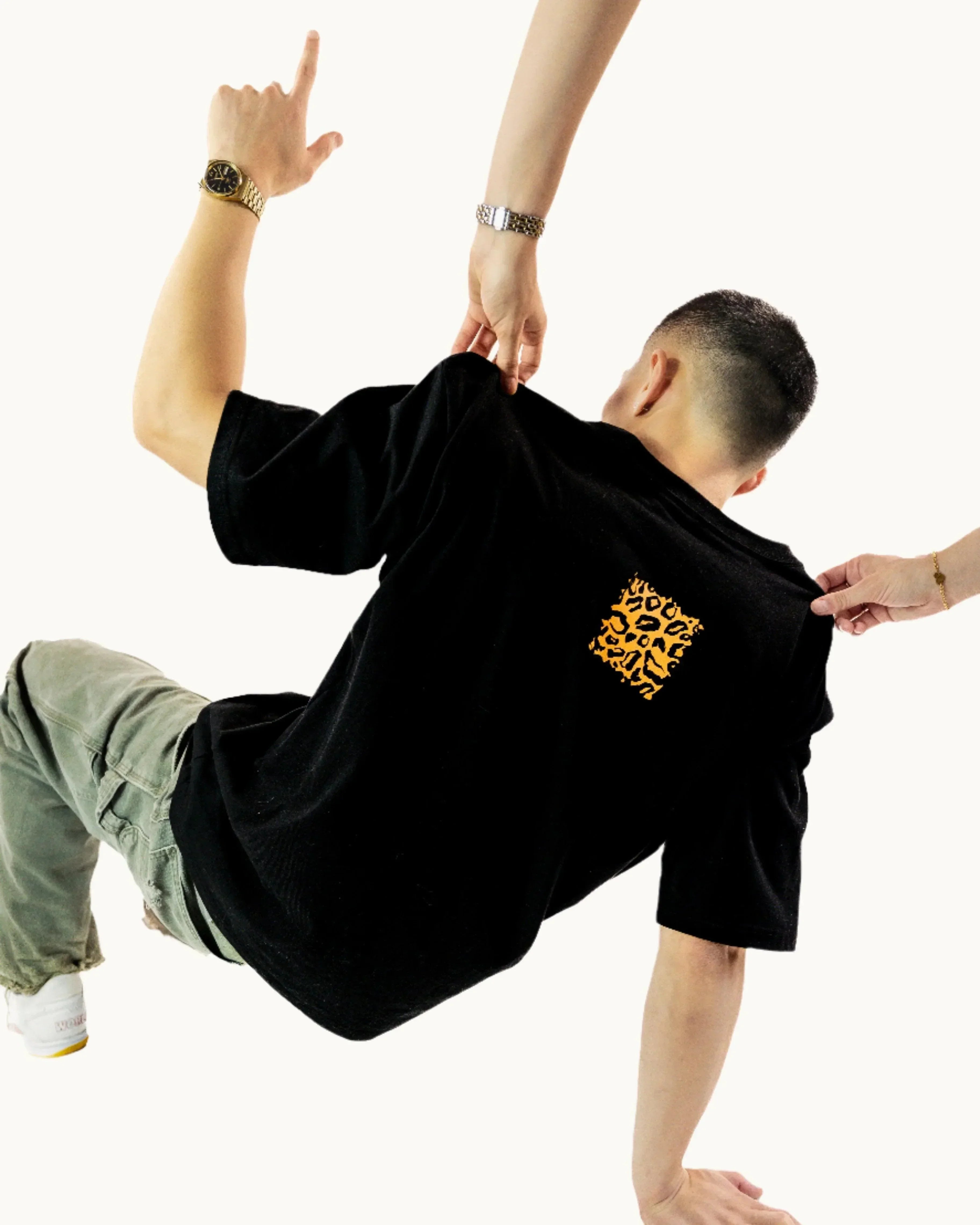 Man wearing black t-shirt with yellow leopard print, olive pants, and white sneakers