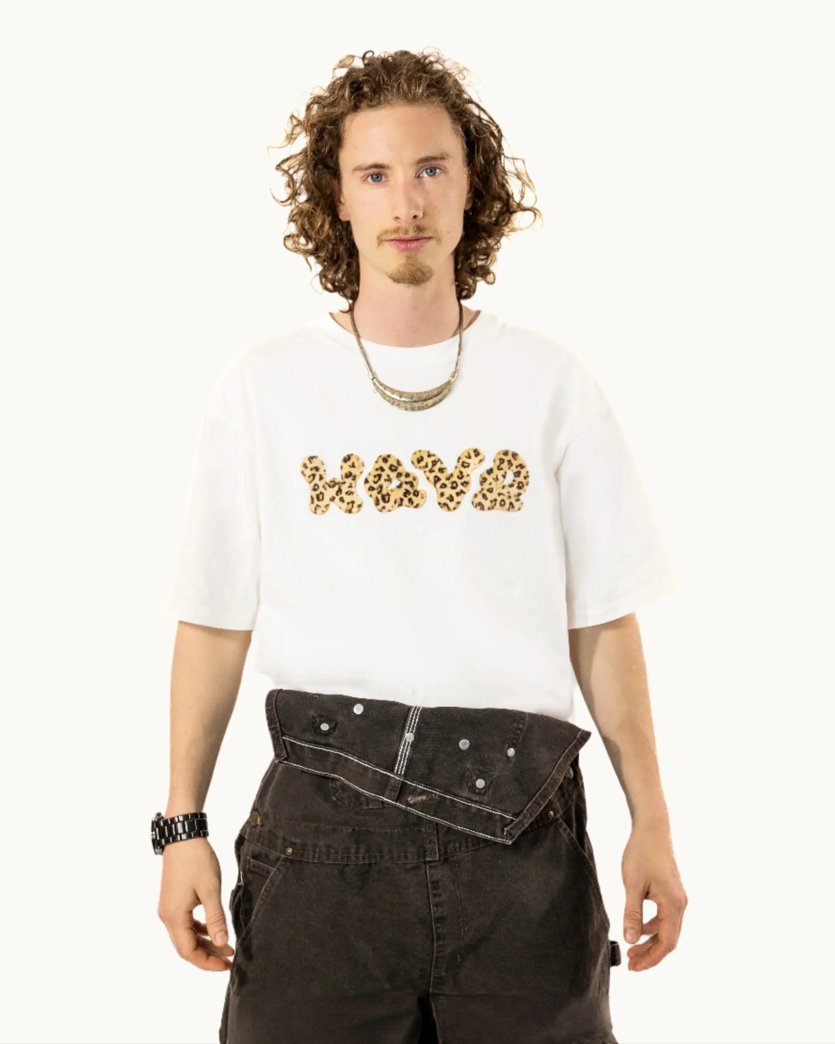 Man wearing white HAVVA t-shirt with leopard print letters and dark oversized pants
