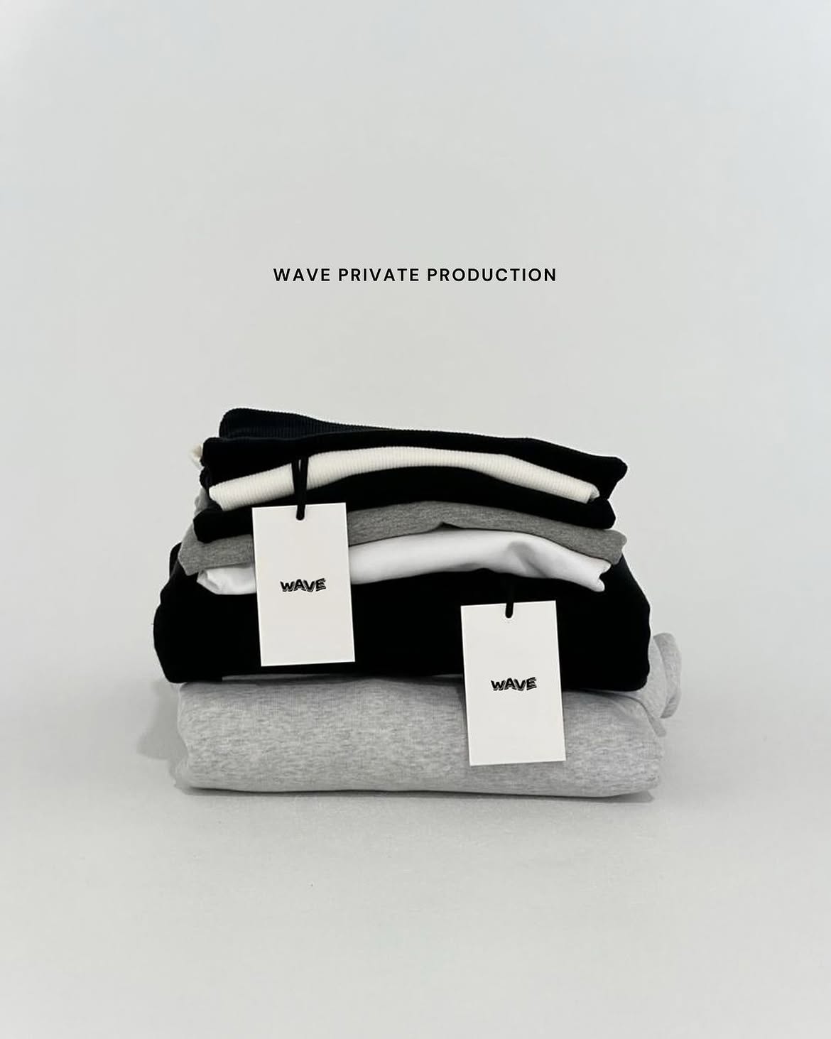 WAVE PRIVATE PRODUCTION — folded black, white, and grey apparel with WAVE tags